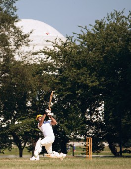 A Washington Cricket League player batting with the Jefferson Memorial in the background, during a game at West Potomac Park in Washington, DC. Photo by Noah Willman. `